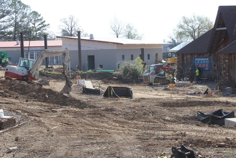 Heavy equipment and cleared ground at the Little Rock Zoo construction site with new buildings taking shape