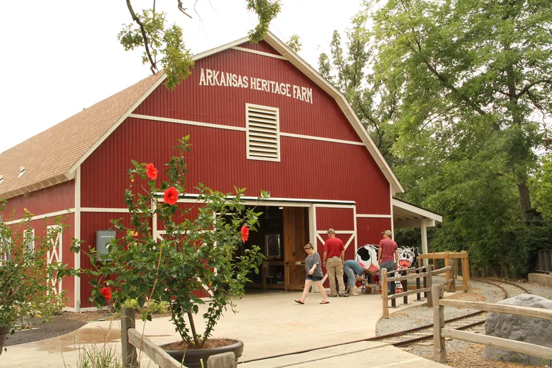 The red barn at the Arkansas Heritage Farm exhibit, with visitors seated on the porch